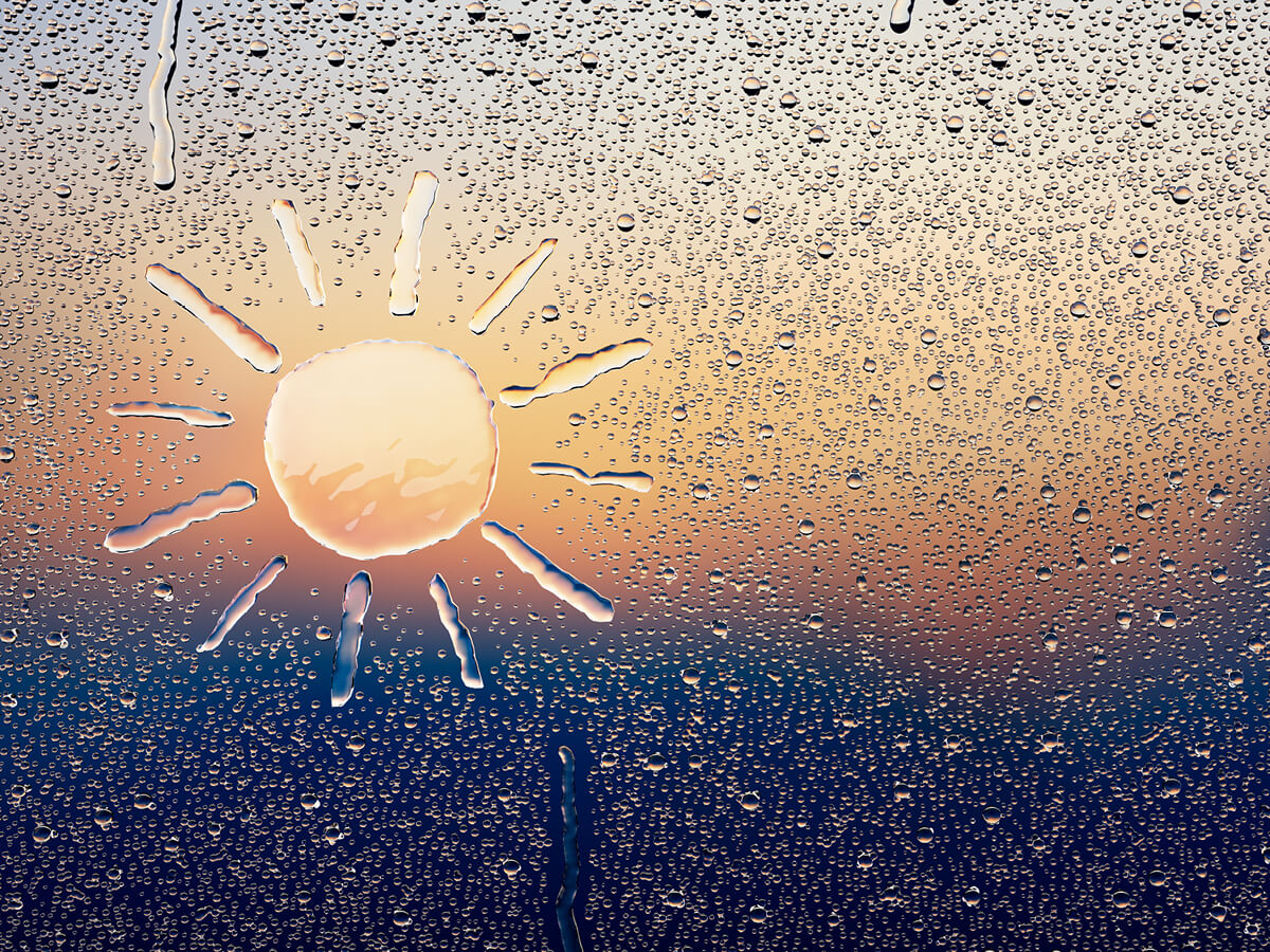 raindrops on a window with a sun drawing